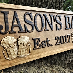 May include: A wooden sign with the text "Jason's Bar Est. 2017" carved into it. The sign features two carved beer mugs with foam on top.