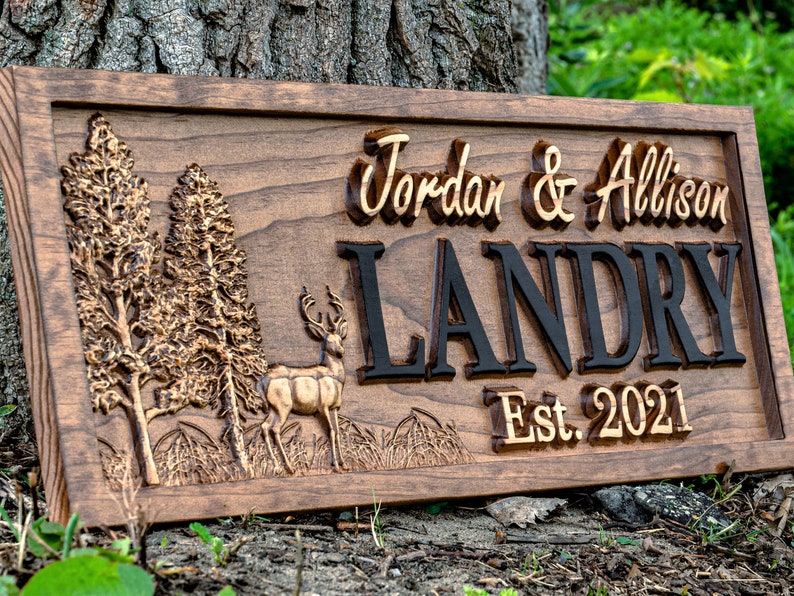 May include: A wooden sign with a carved deer, trees, and the text "Jordan & Allison Landry Est. 2021".
