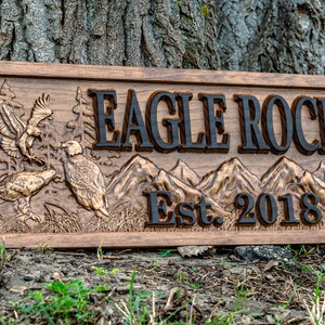 May include: A wooden sign with a carved eagle and mountain scene. The sign reads "Eagle Rock Est. 2018".