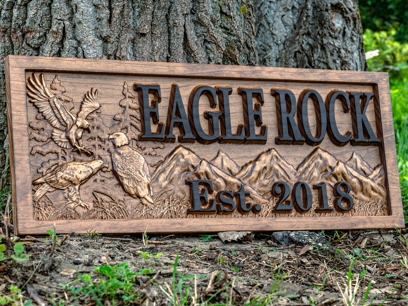 May include: A wooden sign with a carved eagle and mountain scene. The sign reads "Eagle Rock Est. 2018".