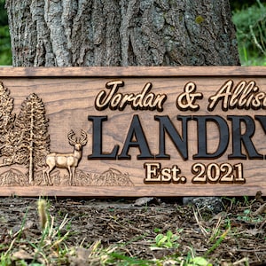 May include: A wooden sign with a carved deer, trees, and the text "Jordan & Allison Landry Est. 2021".