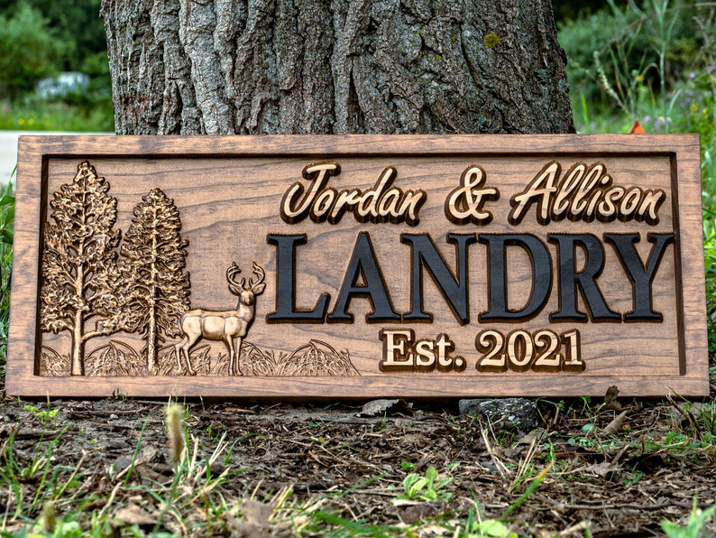 May include: A wooden sign with a carved deer, trees, and the text "Jordan & Allison Landry Est. 2021".