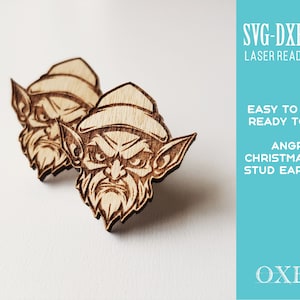 May include: A pair of laser cut wooden stud earrings featuring an angry Christmas elf design. The earrings are ready to be made and cut using SVG, DXF, and EPS files. The text "SVG-DXF-EPS Laser Ready Files" is in the top right corner of the image. The text "EASY TO MAKE READY TO CUT ANGRY CHRISTMAS ELF STUD EARRINGS" is in the top right corner of the image. The text "OXEE" is in the bottom right corner of the image.