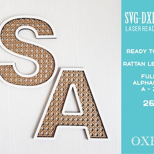 Op de afbeelding: Twee lasergesneden houten letters, "S" en "A", met een geweven rotanpatroon. De letters zijn wit met een bruin rotanontwerp. De afbeelding bevat de tekst "SVG-DXF-EPS LASER READY FILES", "READY TO CUT RATTAN LETTERS", "FULL ALPHABET A-Z", "26" en "OXEE".