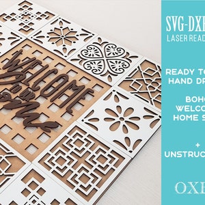 Puede incluir: Un letrero de bienvenida de madera blanca con una inscripción en marrón "Welcome Home" y intrincados patrones geométricos. El letrero está listo para ser cortado con un cortador láser.