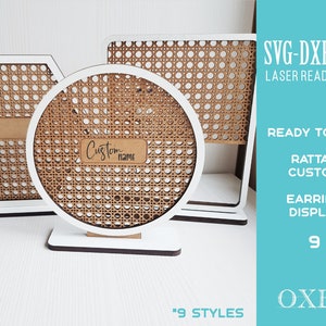 May include: Three white wooden earring display stands with a rattan pattern. The stands are in the shape of a hexagon, a circle, and a rectangle. The circle stand has a label that says "Custom name".