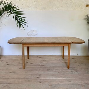Puede incluir: Una mesa de comedor extensible de madera clara con una tapa rectangular redondeada y cuatro patas. La mesa est&aacute; hecha de madera maciza y tiene un acabado natural.