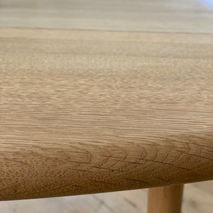 Puede incluir: Primer plano de una mesa de madera de color marr&oacute;n claro con un borde redondeado. La mesa tiene un patr&oacute;n de veta de madera natural.