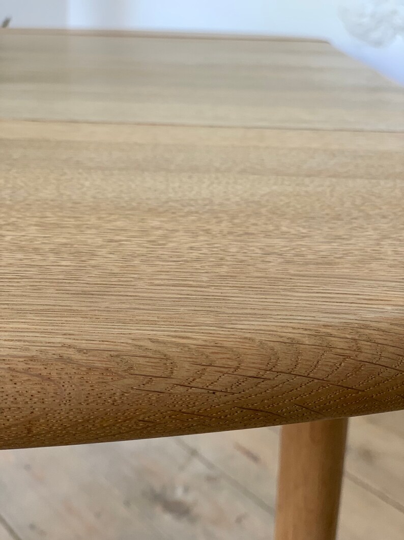 Puede incluir: Primer plano de una mesa de madera de color marr&oacute;n claro con un borde redondeado. La mesa tiene un patr&oacute;n de veta de madera natural.