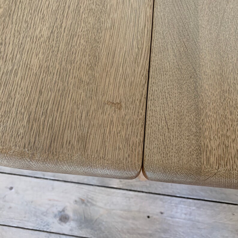 Puede incluir: Primer plano de una mesa de madera clara con un peque&ntilde;o rasgu&ntilde;o en la superficie. La mesa est&aacute; hecha de dos piezas de madera unidas.