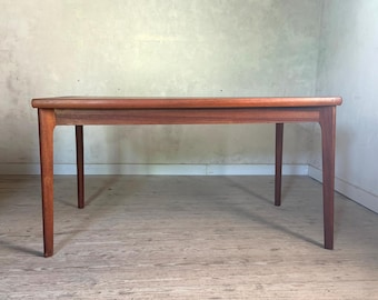 Op de afbeelding: Een rechthoekige houten eettafel met een warme bruine afwerking, voorzien van een glad, vlak tafelblad en vier rechte, licht taps toelopende poten die vanuit de hoeken uitsteken voor een stabiele en evenwichtige structuur van het meubel.