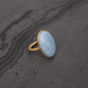 May include: A gold ring with a light blue oval gemstone.
