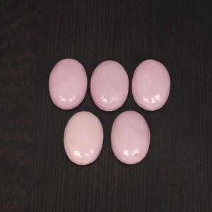 May include: Six oval-shaped pink gemstones with a glossy finish.