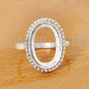 Puede incluir: Anillo de plata con engaste de bisel para una piedra de forma ovalada. El bisel está decorado con una fila de pequeñas cuentas.