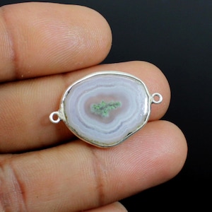 Op de afbeelding: Een witte agaat hanger met een groen centrum, gezet in een zilveren bezel met twee springringen. De hanger is ovaalvormig en heeft een gladde, gepolijste afwerking.
