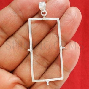 Puede incluir: Engaste de bisel para colgante de plata con forma rectangular y cuatro garras a cada lado. El colgante está diseñado para sujetar una piedra preciosa u otro material.