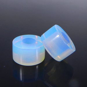 May include: Two iridescent blue and white opalite beads with a hole in the center. The beads are round and have a smooth, polished finish.