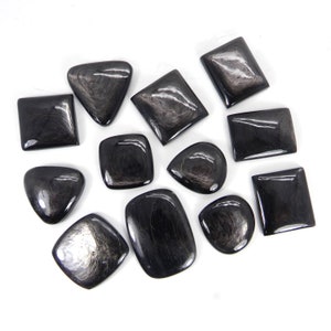 Puede incluir: Una colección de 12 cabujones de obsidiana negra con vetas plateadas. Los cabujones son de varias formas, incluyendo cuadrada, rectangular, ovalada y de lágrima.