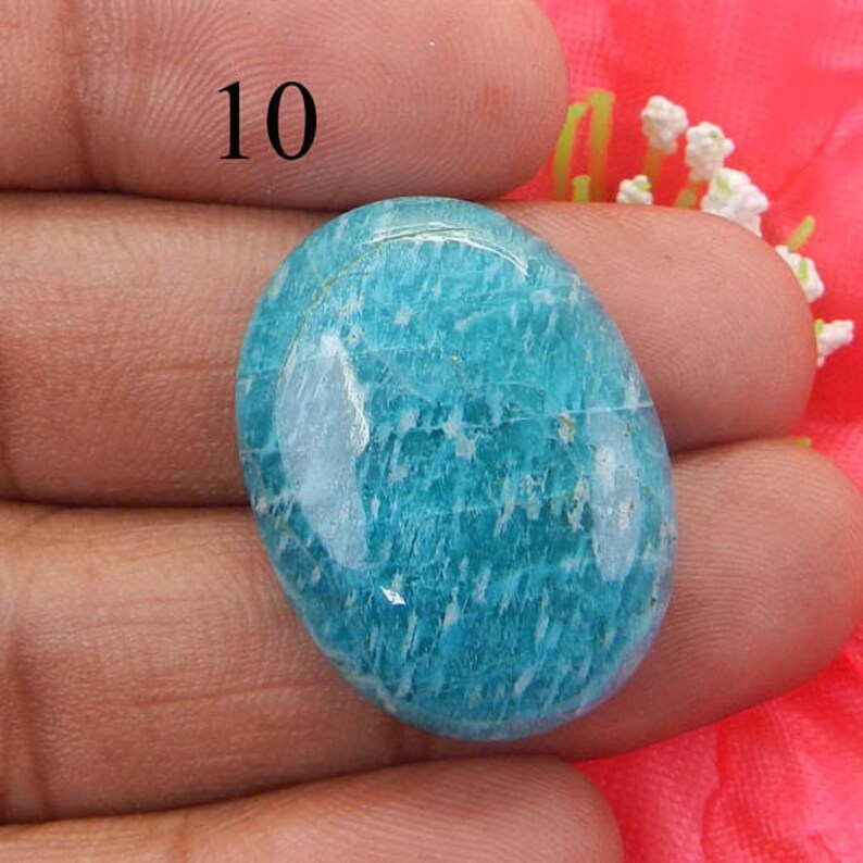 Puede incluir: Una piedra preciosa de amazonita lisa, de forma ovalada, azul claro con un patr&oacute;n de m&aacute;rmol blanco y verde.