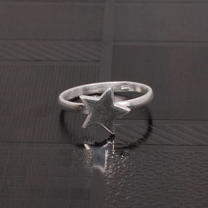 Peut inclure: Une bague en argent avec un motif d'étoile. La bague est en argent sterling et a une finition polie.