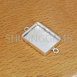 Peut inclure: Pendentif en argent avec deux anneaux de saut. Le pendentif est rectangulaire et a une finition lisse et polie.