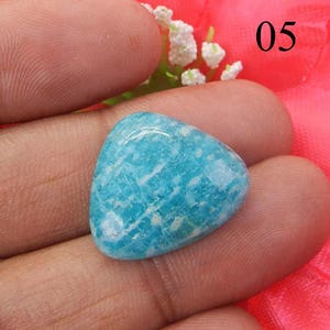 Puede incluir: Una piedra preciosa triangular de color azul claro con un patr&oacute;n de m&aacute;rmol blanco. La piedra preciosa mide aproximadamente 2,5 cm.