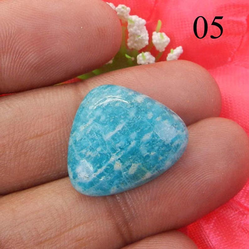 Puede incluir: Una piedra preciosa triangular de color azul claro con un patr&oacute;n de m&aacute;rmol blanco. La piedra preciosa mide aproximadamente 2,5 cm.