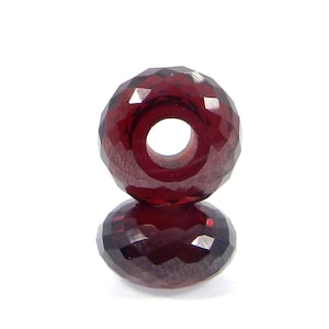 Peut inclure: Une perle de pierre précieuse rouge facetée avec un trou au centre. La perle est ronde et a une finition brillante et polie.