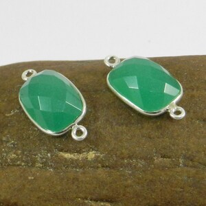 May include: Two green gemstone connector charms with silver settings. Each charm has two loops for attaching to jewelry.