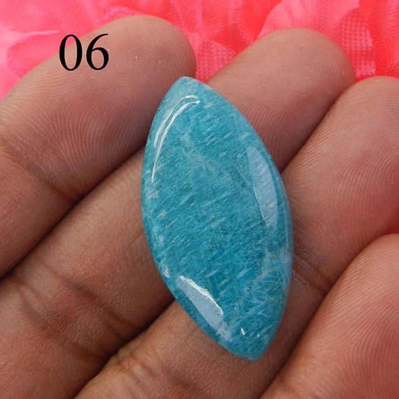 Puede incluir: Una piedra preciosa azul claro en forma de l&aacute;grima con una superficie lisa y pulida. La piedra preciosa tiene un patr&oacute;n sutil y estriado.