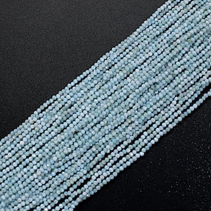 May include: A strand of light blue faceted gemstone beads. The beads are small and round, and they are strung together on a clear thread.
