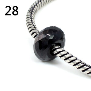 Peut inclure: Un charme de perle facetté noir sur un bracelet en chaîne serpent argenté.