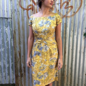 May include: A yellow and gray floral print dress with a square neckline and short sleeves. The dress has a fitted bodice and a slightly flared skirt.