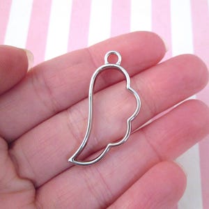 May include: Silver metal pendant shaped like an angel wing. The pendant has a loop at the top for attaching a chain or cord.