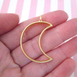 May include: Gold metal crescent moon charm pendant with a loop at the top for attaching to a necklace or bracelet.