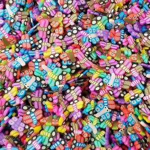 May include: A large quantity of colorful butterfly-shaped charms. The charms are made of polymer clay and have a variety of colors and patterns.