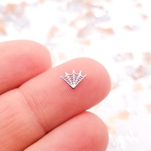 May include: A silver spiderweb charm with a triangular shape. The charm is small and delicate, perfect for adding a touch of Halloween to crafts or jewelry.