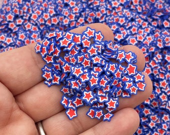 Op de afbeelding: Een close-up van een hand die een stapel rode, witte en blauwe stervormige sprinkles vasthoudt. De sprinkles zijn klein en perfect voor het versieren van cakes, cupcakes en andere desserts.