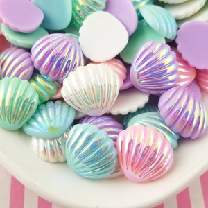 May include: A collection of pastel-colored seashell and irregular-shaped resin beads in a white bowl. The beads are in shades of pink, purple, blue, and green, with iridescent highlights. Ideal for crafting and jewelry making.