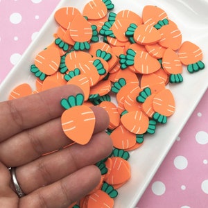 May include: A white plate filled with orange and green carrot-shaped embellishments. The embellishments are made of a soft, pliable material, possibly foam or rubber.
