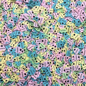 May include: A large pile of colorful heart-shaped foam stickers with black dots and the word "OUIJA" printed on them.