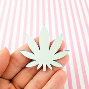 Peut inclure: Une découpe de feuille de marijuana en miroir argenté. La feuille est un motif populaire pour l'artisanat et la décoration.