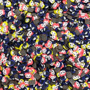 May include: A large assortment of colorful resin charms featuring various cartoon faces, hearts, and geometric patterns. The charms are a mix of pink, yellow, blue, black, and brown.