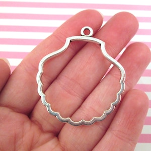 May include: Silver metal pendant shaped like a seashell with a scalloped edge and a loop at the top for hanging.