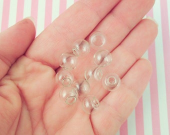 May include: A hand holding a group of clear glass beads. The beads are round and have a smooth surface.