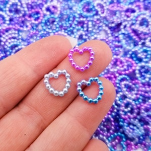 May include: Three heart-shaped charms made of small iridescent pearls. The charms are in shades of pink, blue, and light blue.
