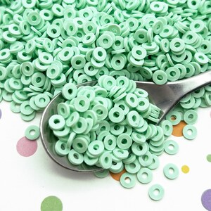 Puede incluir: Un montón grande de sprinkles de donut de plástico verde menta, con una cucharada de sprinkles en una cuchara de plata.
