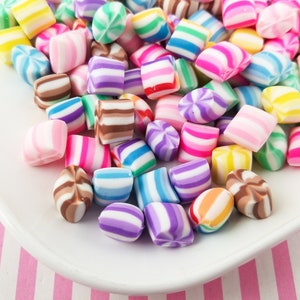 May include: A collection of colorful candy-like squares with stripes and swirls. The candies are arranged on a white plate.