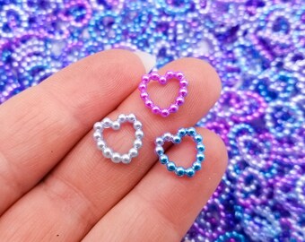 Könnte beinhalten: Drei herzförmige Charms aus kleinen schillernden Perlen. Die Charms sind in den Farben Pink, Blau und Hellblau.