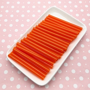 May include: A white rectangular plate filled with 20 orange plastic drinking straws.